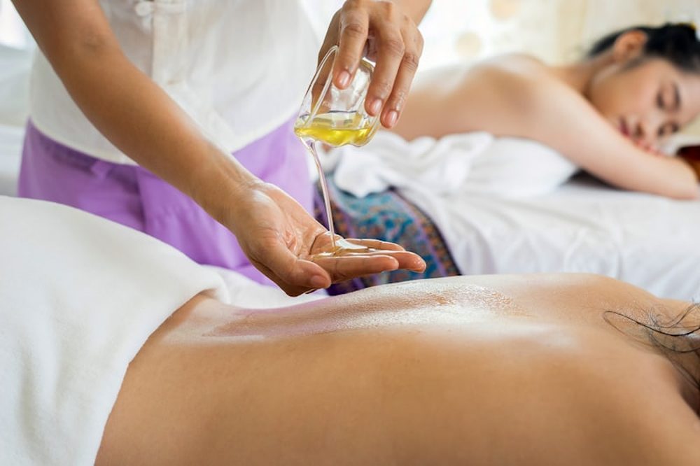 Massage therapist pouring warm oil for a full body massage session near Reading, PA